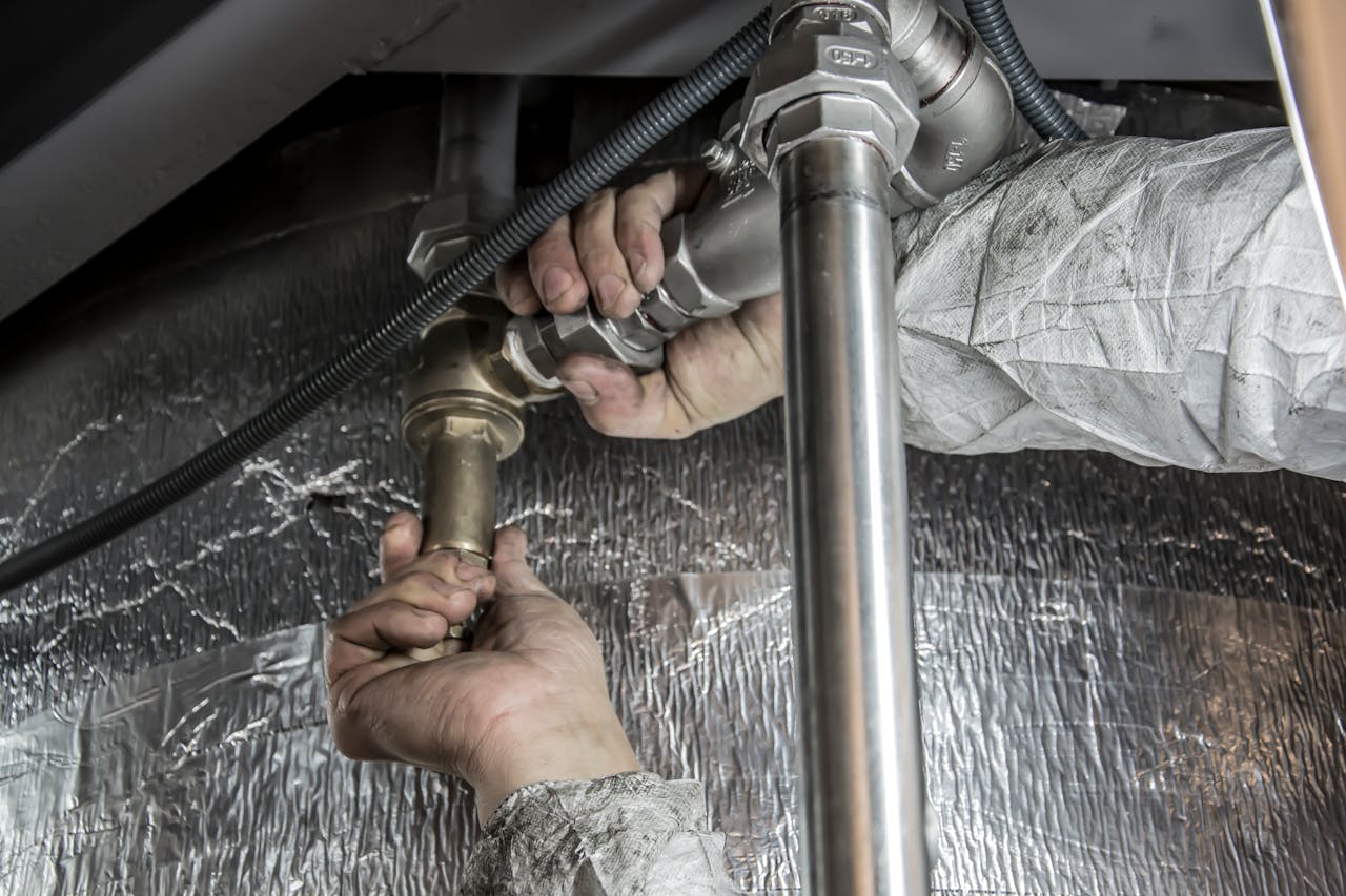 Close-up of a plumbers hands installing steel pipes indoors, showcasing skilled manual work.